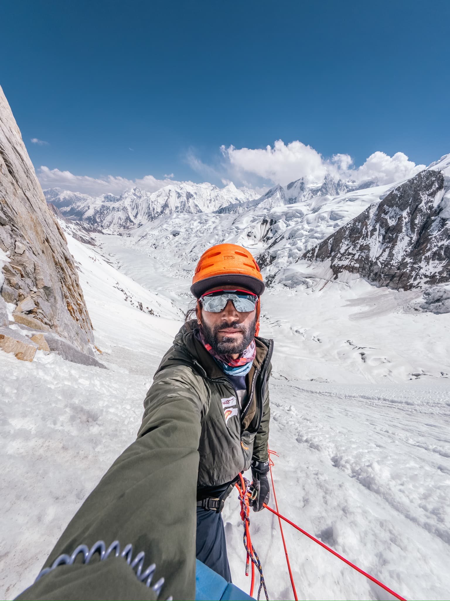 Mueez on a snow ridge with glacier valleys and peaks below