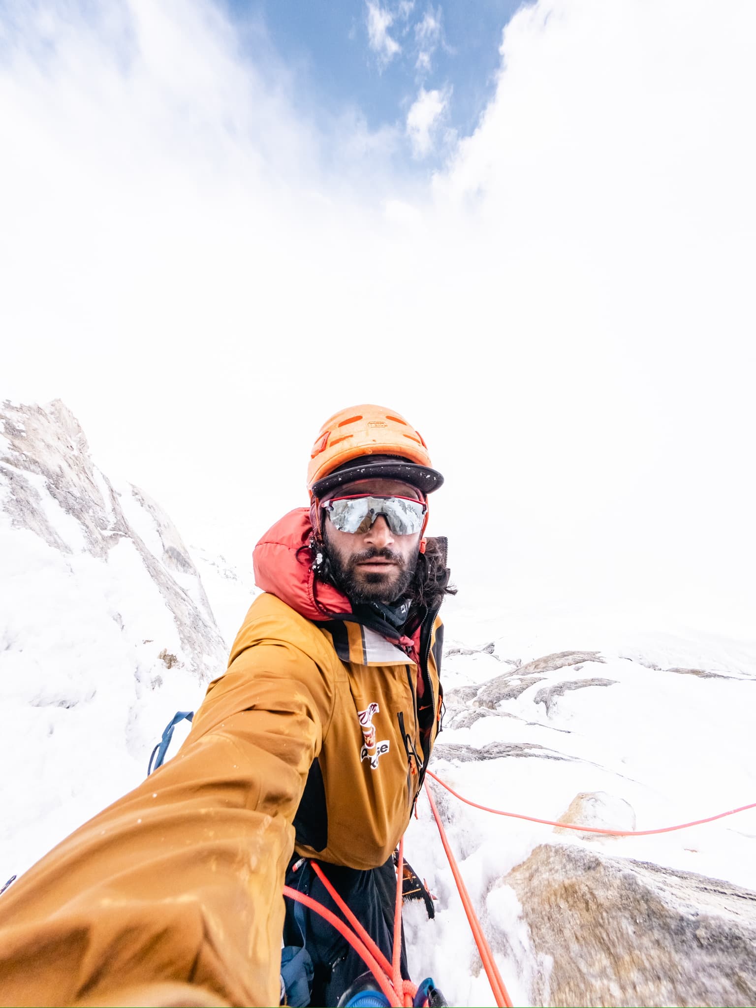 High-altitude climbing selfie in a yellow technical jacket