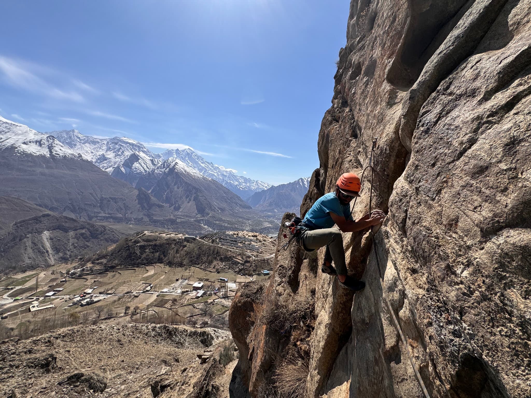 Lead climbing above terraced fields and snow peaks in Hunza