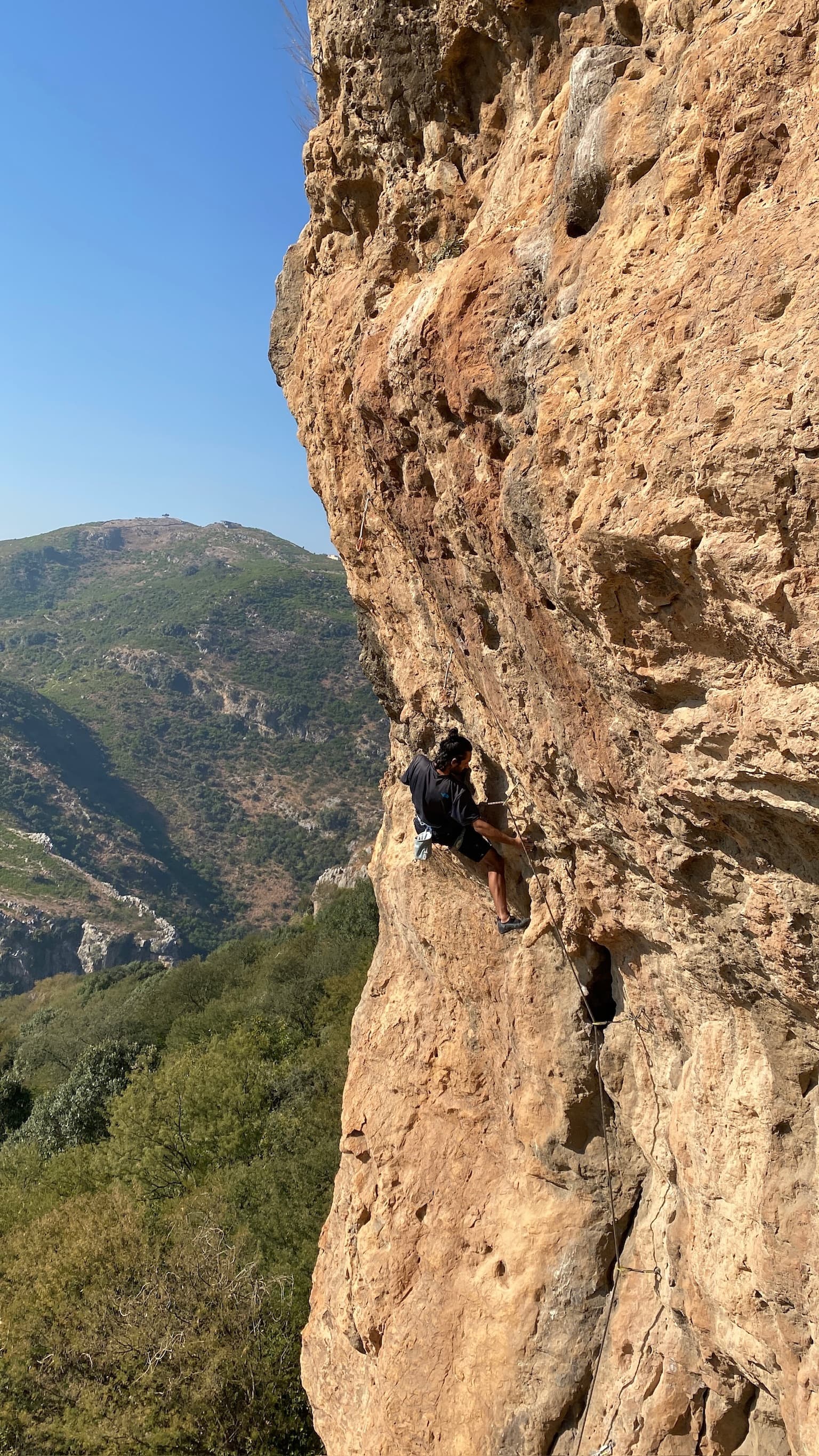 Vertical rock climb overlooking a green mountain valley