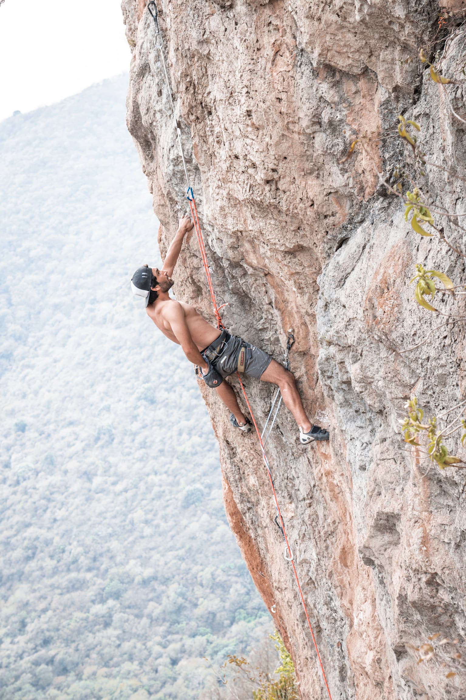 Exposed rock climbing on a steep wall overlooking the valley