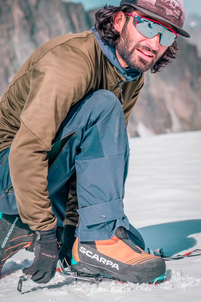 Mueez fitting crampons on a high snowfield before climbing